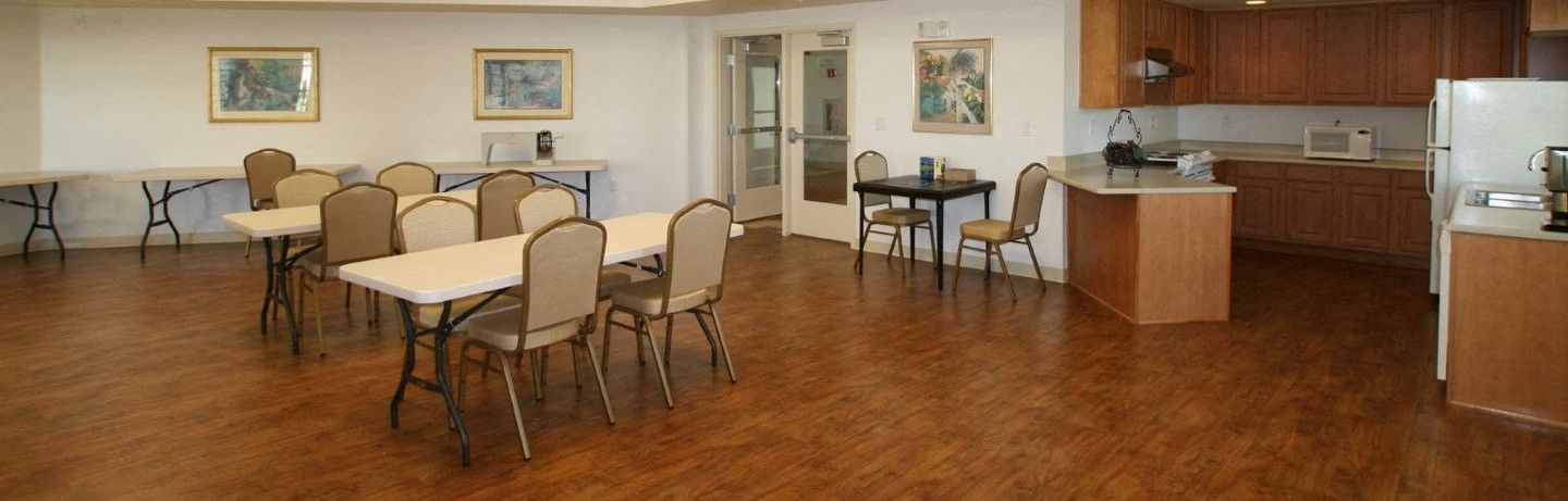 image of community/game room with  tables and kitchen in the background